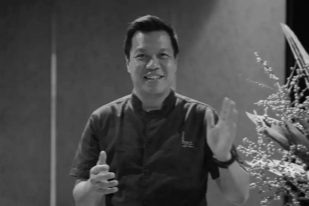 Chef LG Han in black uniform smiling and gesturing while sharing culinary stories