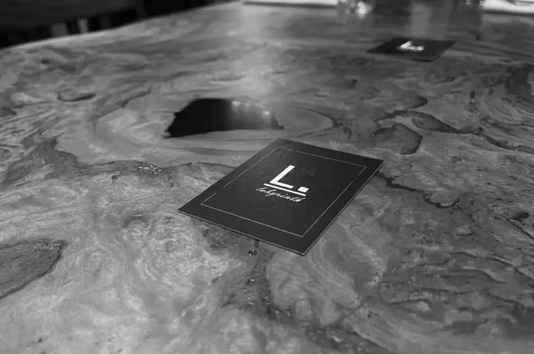 Labyrinth restaurant business card with logo on textured wooden table surface