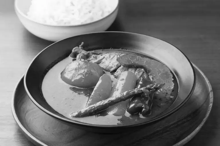 Japanese soup curry with vegetables and meat in rich broth served with steamed rice bowl