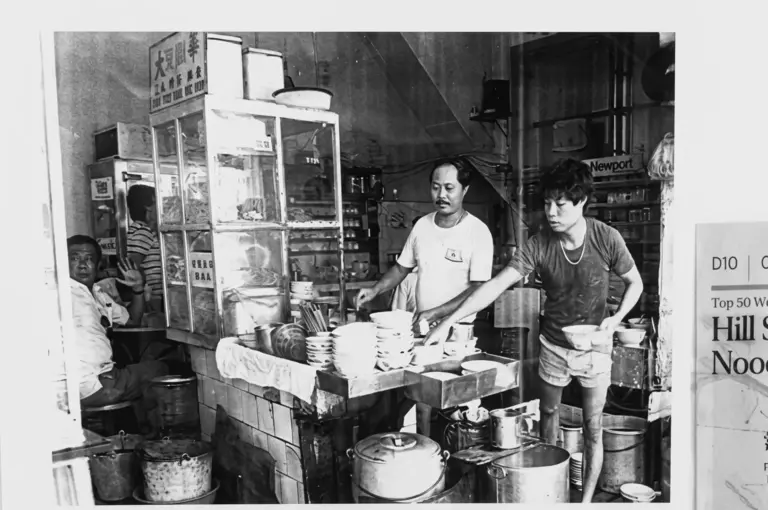 Historical black and white photograph of Hill Street Tai Hwa Pork Noodle stall from the past showing workers serving customers at the original food counter
