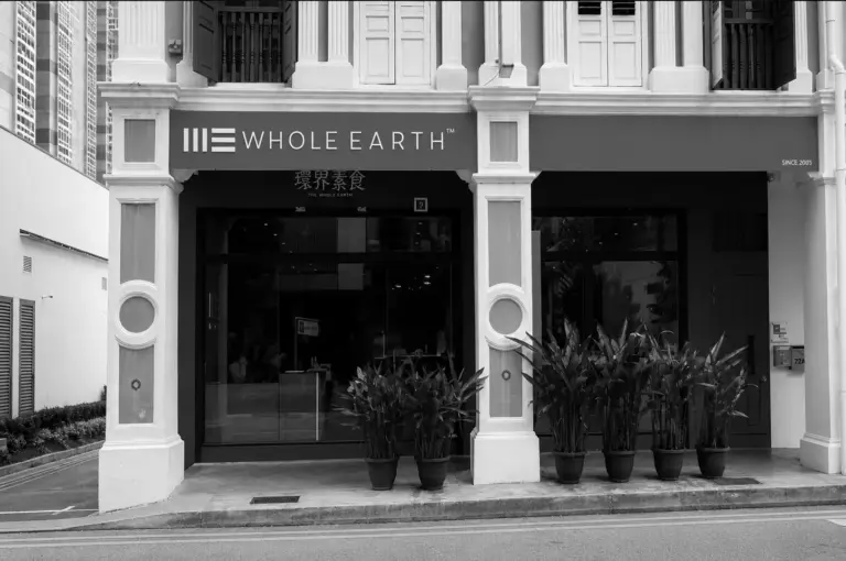 Exterior shot of Whole Earth restaurant located in a heritage shophouse with potted plants