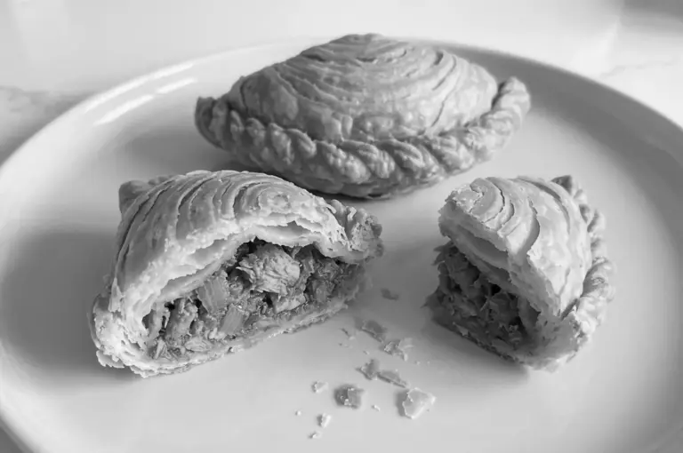 Curry puff cut open revealing savory meat filling inside flaky pastry layers
