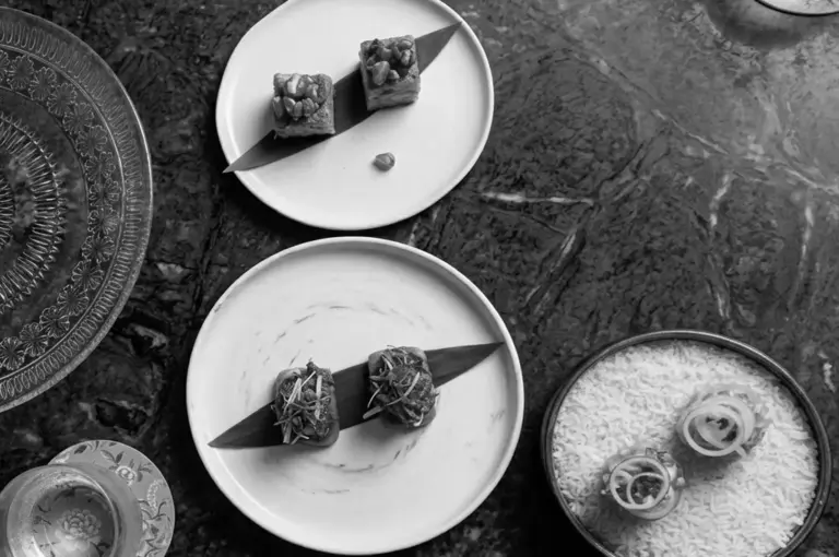 Elegantly plated Peranakan dishes on white plates with decorative serving pieces at Candlenut
