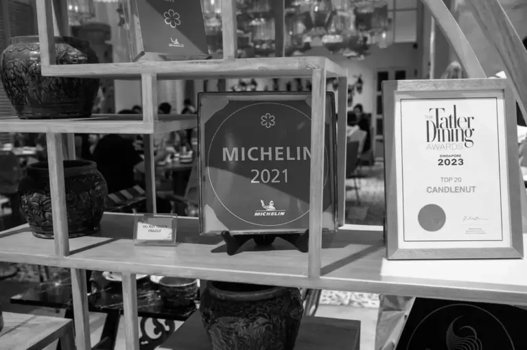 Michelin 2021 and Tatler Dining Awards 2023 display for Candlenut restaurant on wooden shelving