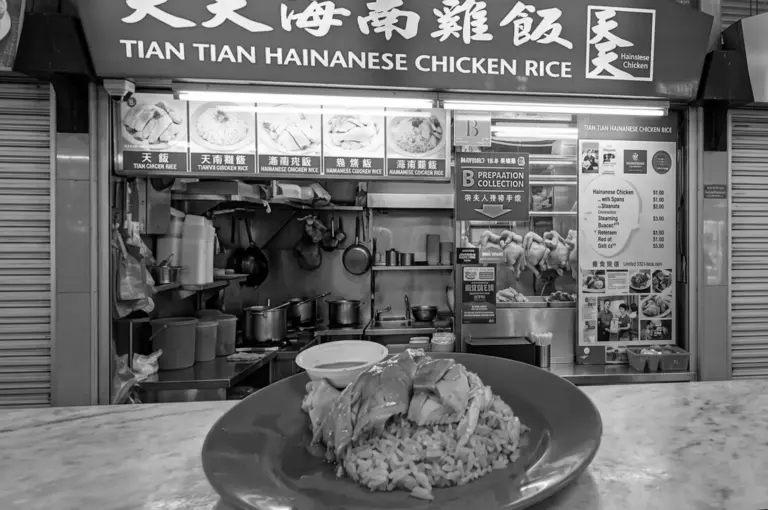 A plate of Hainanese chicken rice sitting on a table in front of the Tian Tian Hainanese Chicken Rice stall