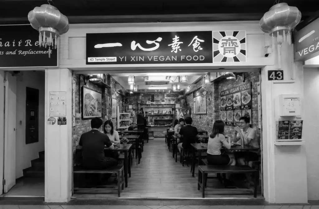 Exterior of Yi Xin Vegan Food restaurant with warm lighting and welcoming indoor dining area.