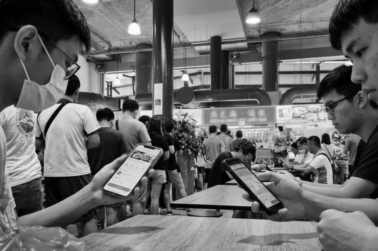 Customers using mobile ordering apps at busy Heng Gi Goose and Duck Rice Michelin hawker stall
