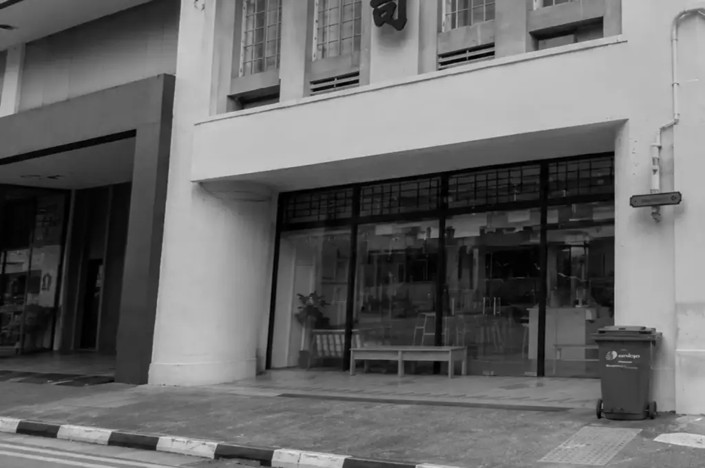 Exterior view of the Apartment Coffee storefront with large glass windows and a bench outside