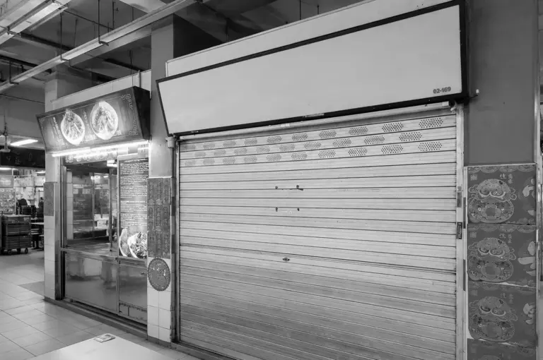 Closed hawker stall with its metal shutter pulled down and blank signboard, highlighting the trend of heritage food vendors shutting down