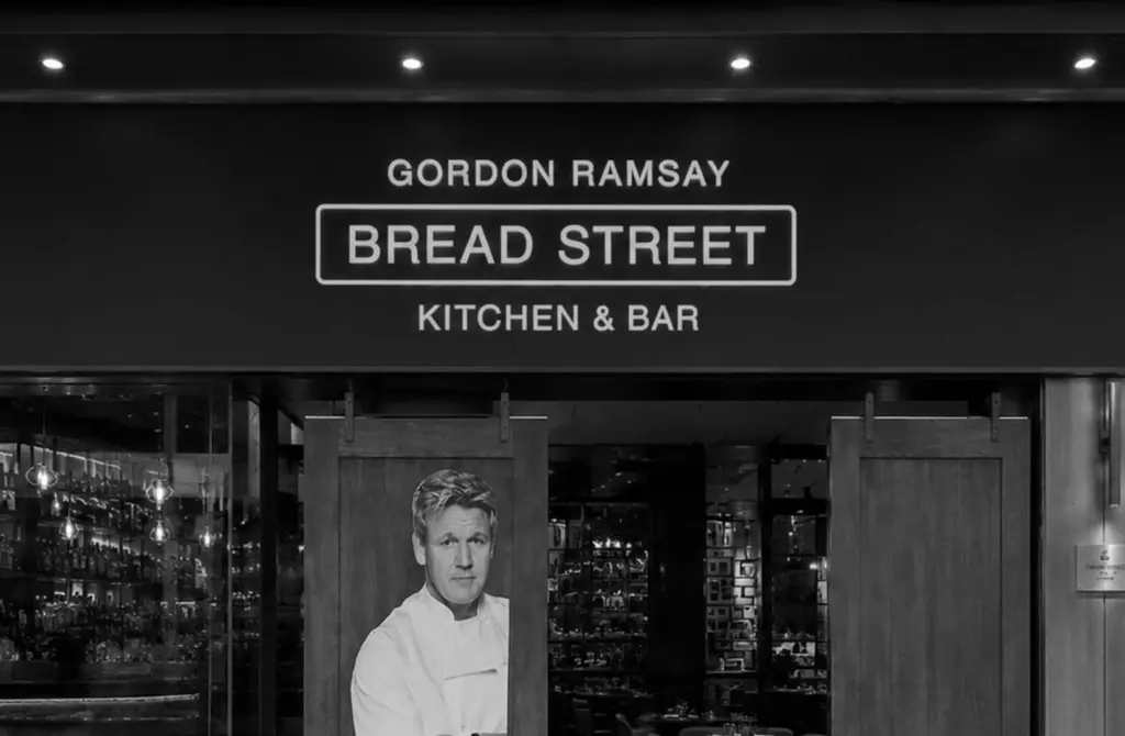The entrance to Gordon Ramsay Bread Street Kitchen & Bar features the restaurant sign and a portrait of the celebrity chef