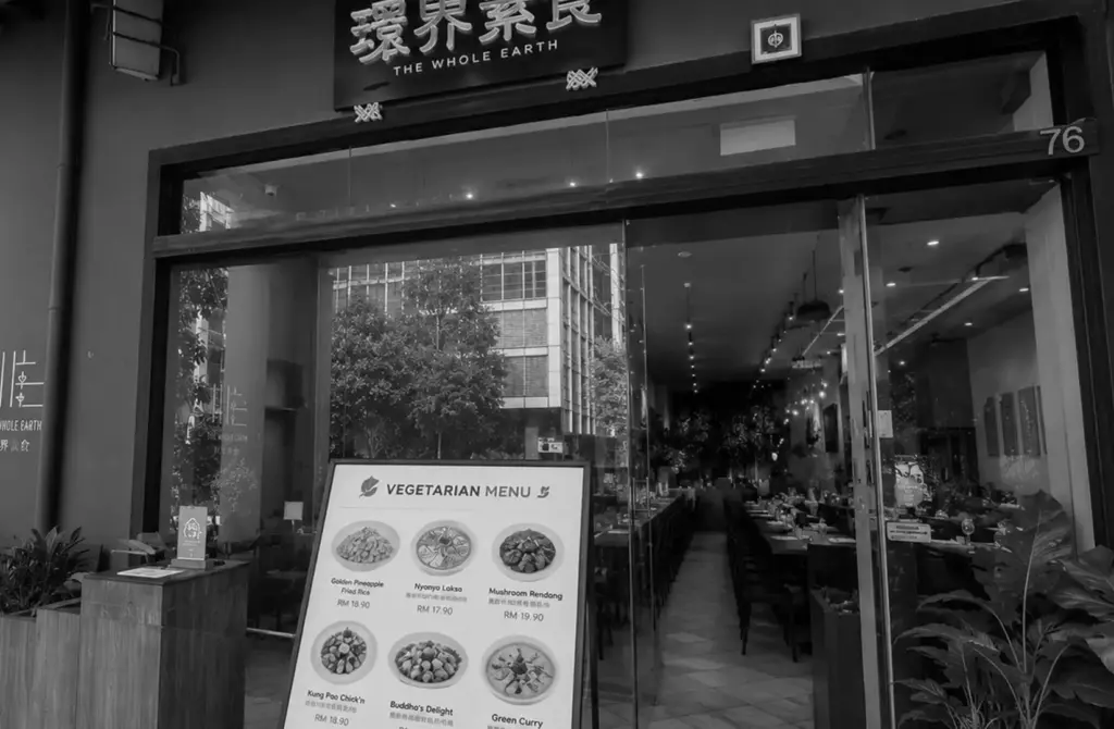Entrance of The Whole Earth vegetarian restaurant with menu display at the storefront.
