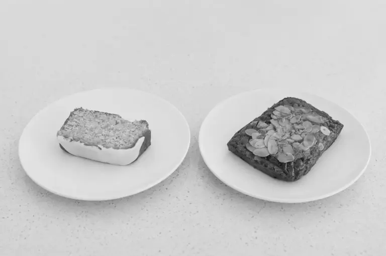 Photo of two plated cafe pastries, one with crumble topping and another with sliced almonds