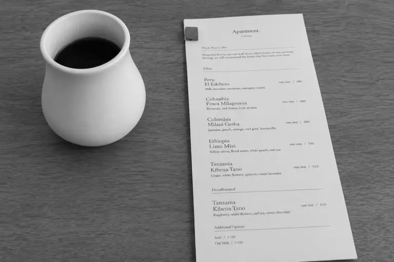 Photo of a white ceramic cup of black coffee next to the Apartment Coffee filter menu