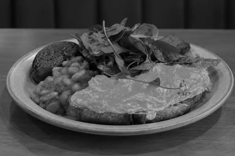 Close-up of a brunch plate with fried egg on toast, baked beans, and mushrooms