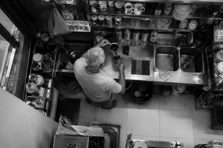 Top-down view of a traditional coffee maker preparing kopi using a cloth filter and metal pots in a kopitiam stall