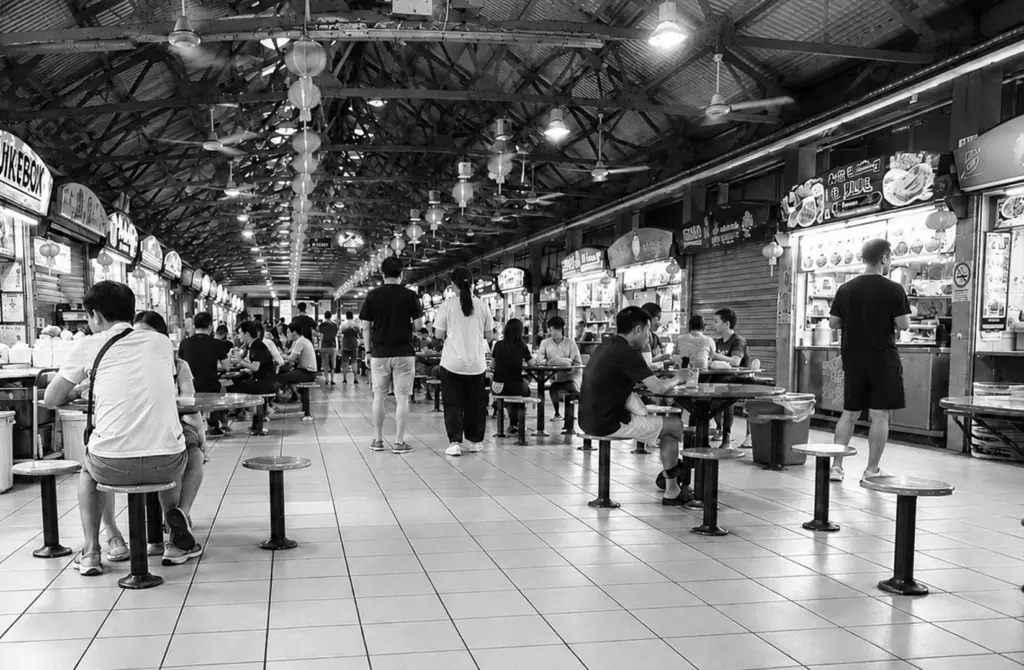 People dining at a spacious Singapore hawker centre with multiple food stalls.