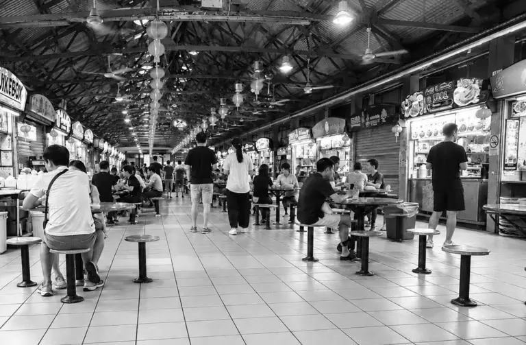 People dining at a spacious Singapore hawker centre with multiple food stalls.