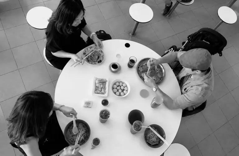 Overhead view of people sharing a meal at a hawker centre table.