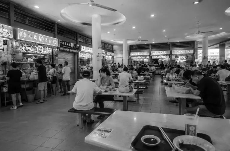 Interior of Tiong Bahru Market food centre with diners and hawker stalls.