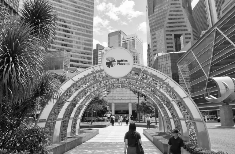 Entrance arch at Raffles Place surrounded by modern skyscrapers in Singapore's financial district.