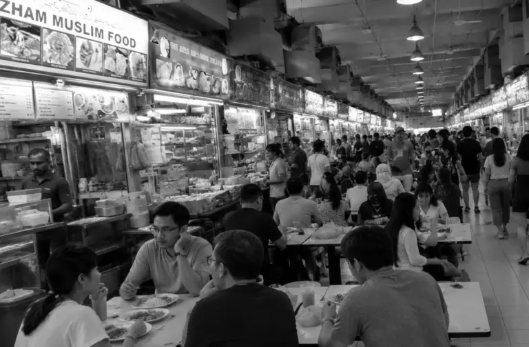 Crowded Tekka Centre food hall with bustling dining and hawker stalls.