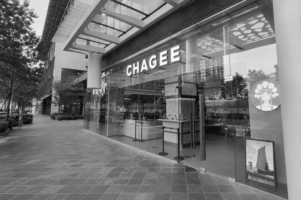 CHAGEE tea store with a modern glass storefront in a contemporary shopping complex, featuring a clean entrance and outdoor walkway.
