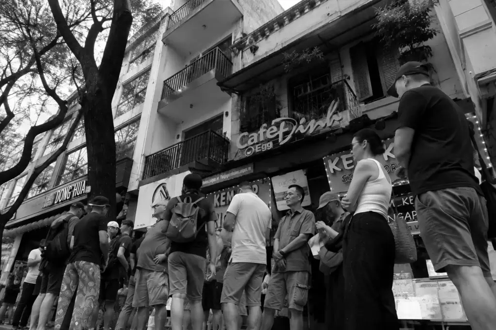 A long line of customers waits outside a popular pop-up restaurant, reflecting the excitement and demand for limited-time dining experiences.