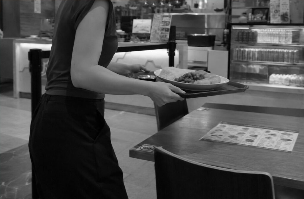 A diner carries a tray of food to a table at a casual restaurant in Singapore.