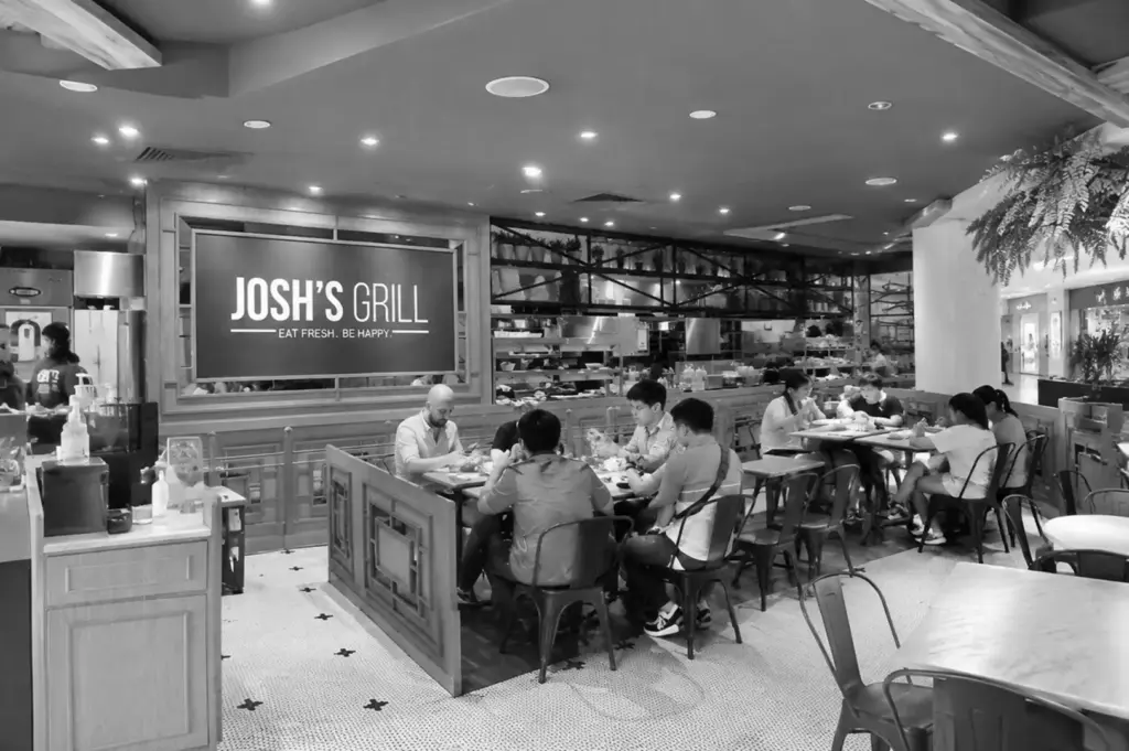 Cozy restaurant dining area with customers enjoying meals in a modern open-kitchen setting.