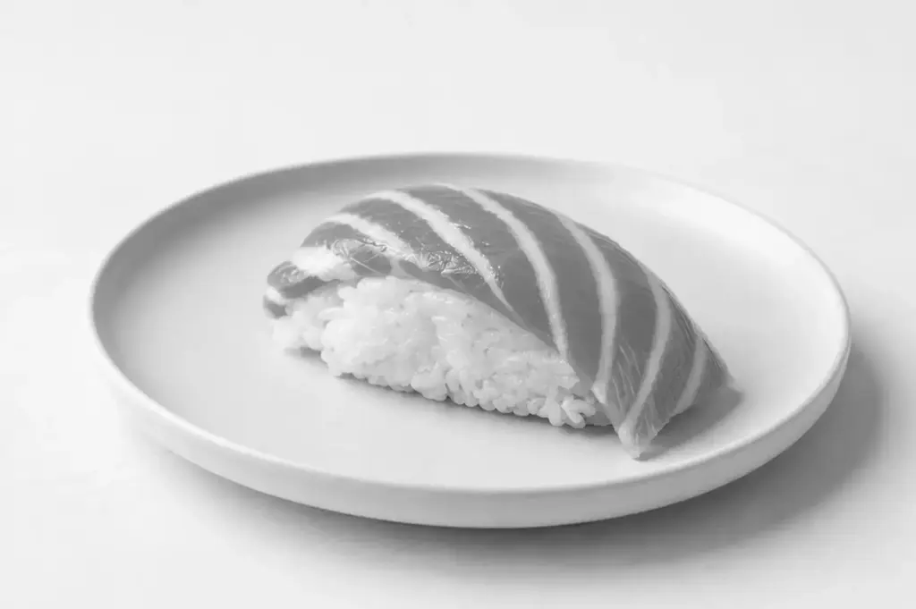 Close-up of fresh silver-skinned fish nigiri sushi served on a white ceramic plate.