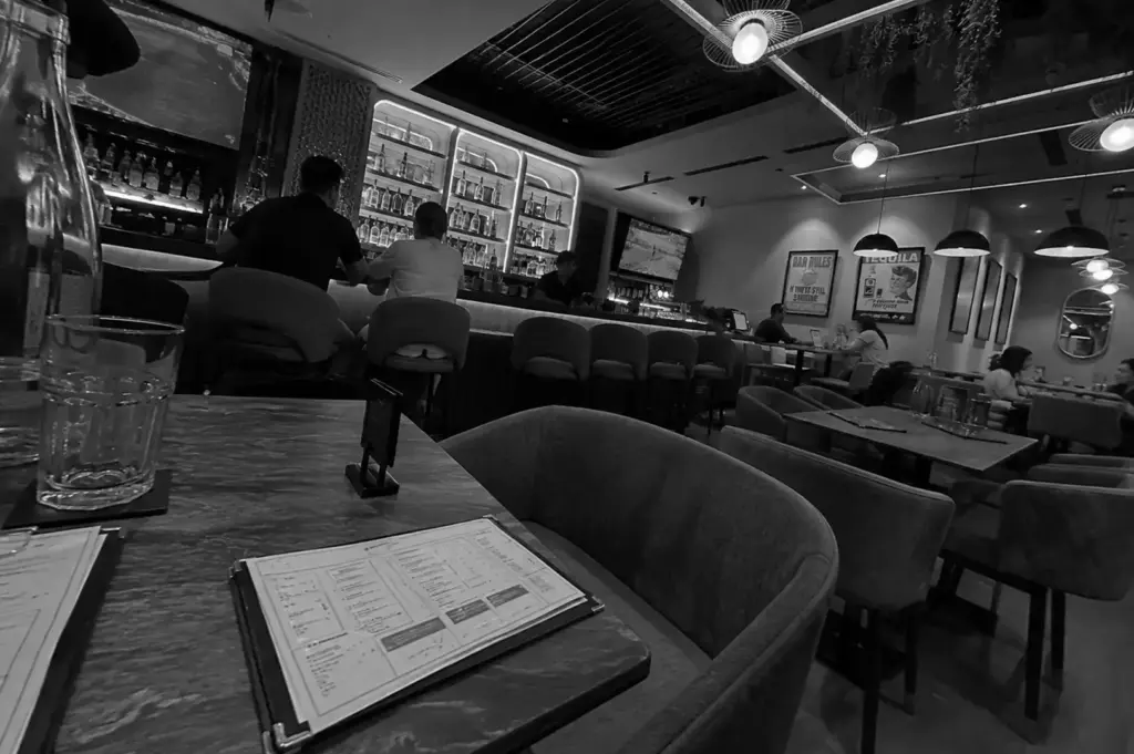 Cozy restaurant interior with bar seating, dining tables, and warm ambient lighting.