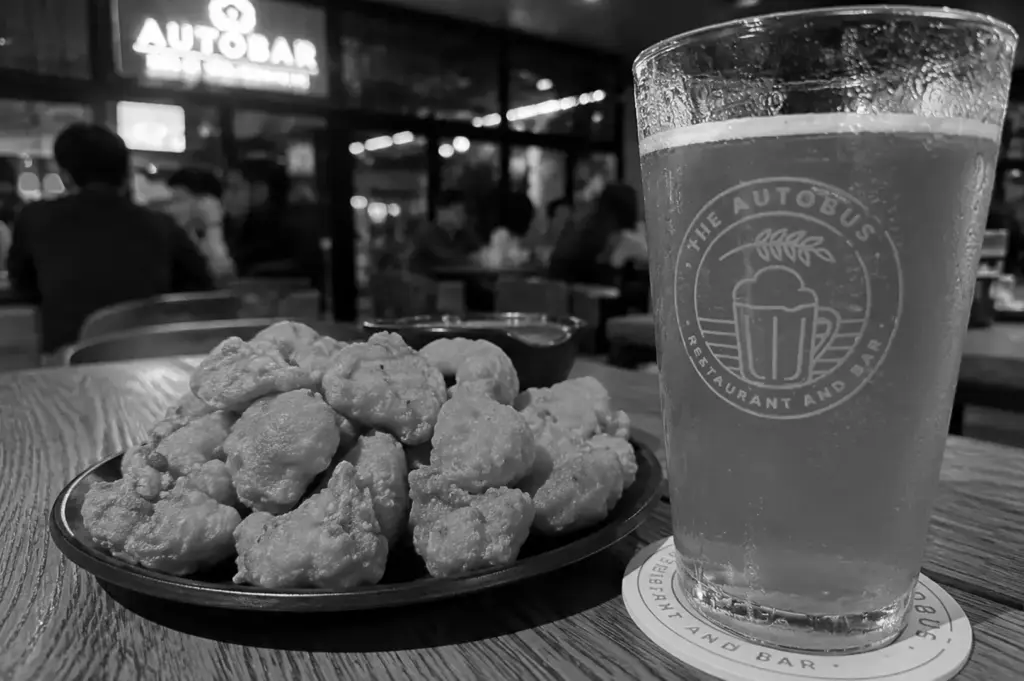 Glass of beer served with crispy fried bites at The Autobus restaurant and bar.