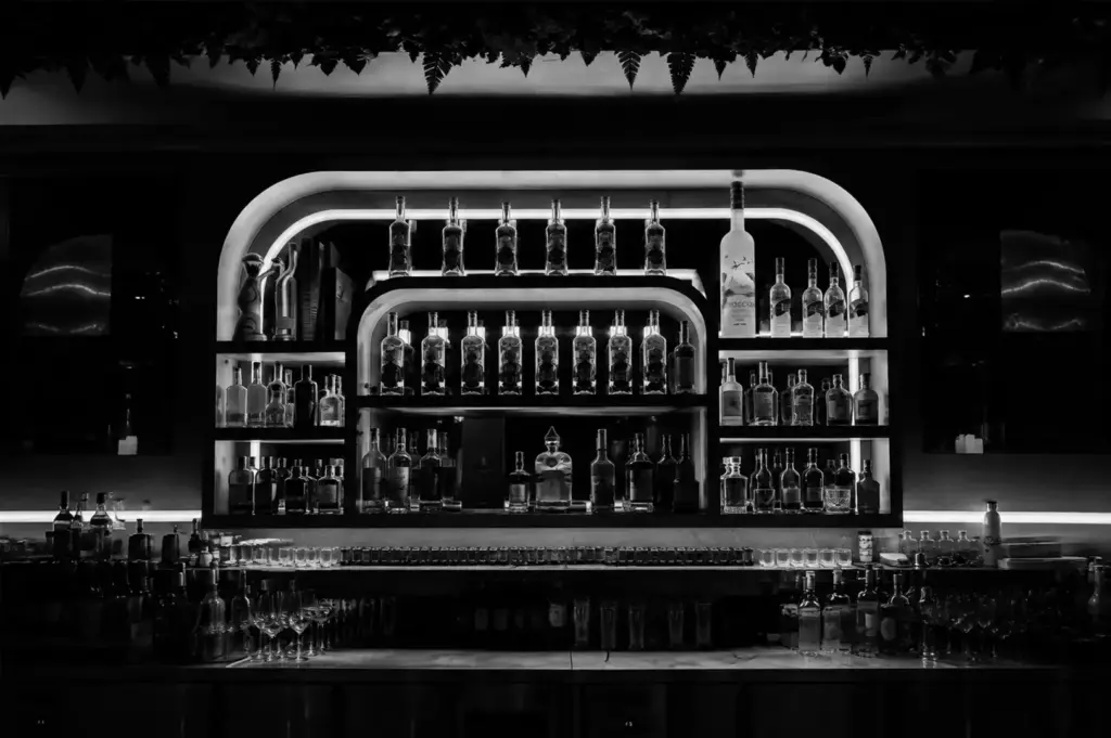 Backlit shelves of premium spirits create an elegant focal point inside Behind The Green Door Singapore.