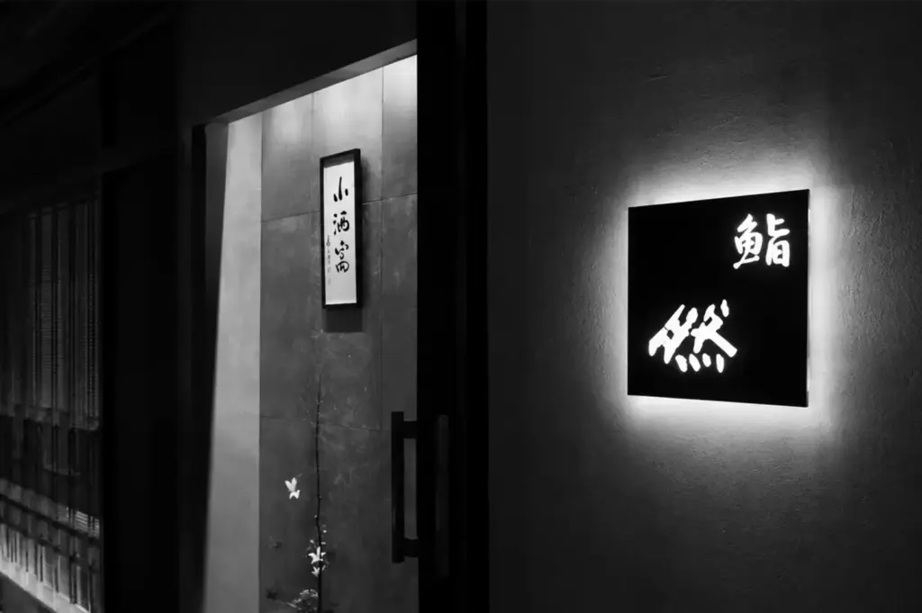 Entrance of Sushi Zen Singapore with a minimalist illuminated sign and elegant Japanese design.