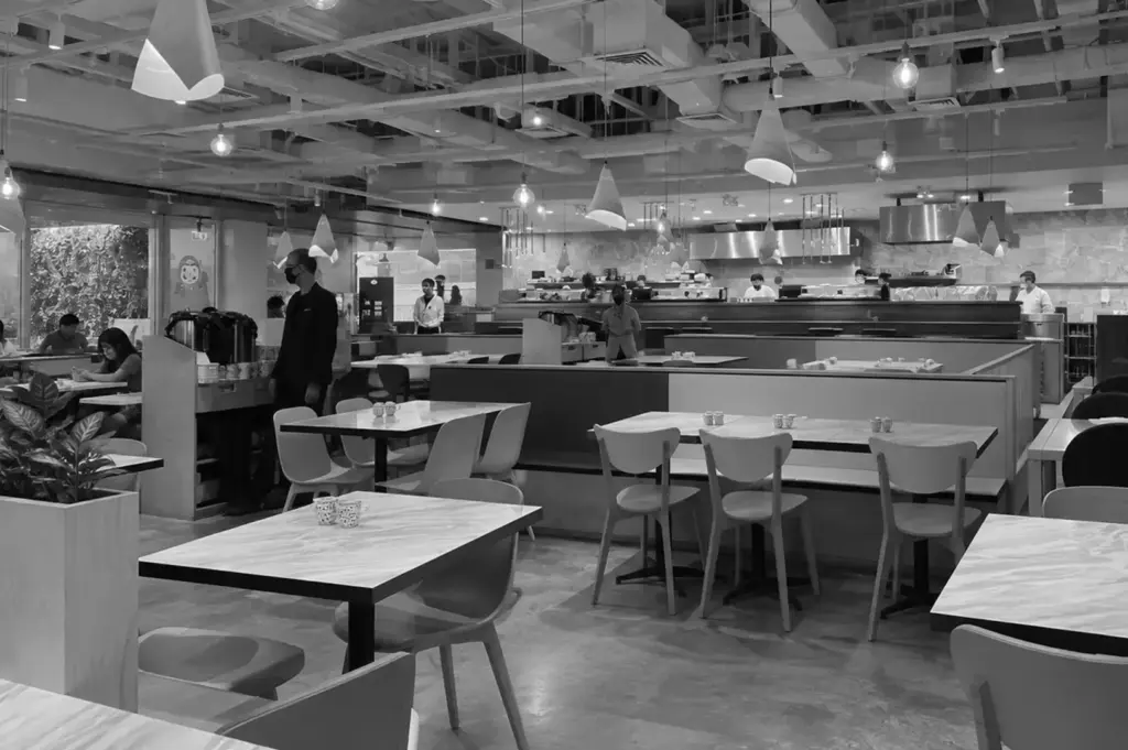 Omoté Singapore restaurant interior with marble dining tables, modern pendant lights, an open kitchen, and contemporary Japanese decor.