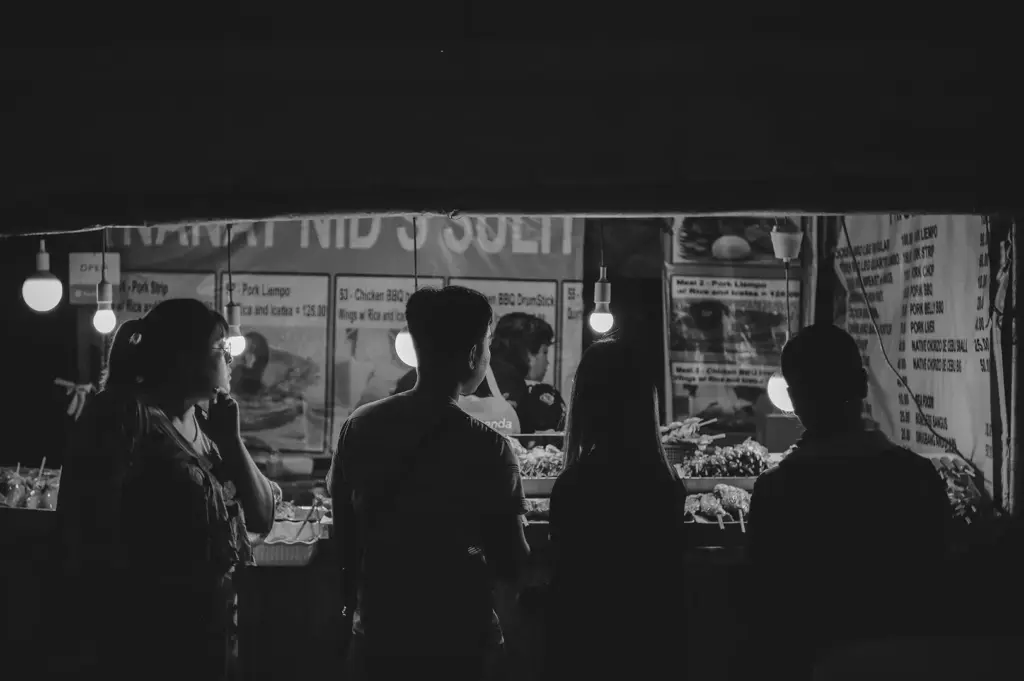 Customers gather around a busy temporary food stall, browsing the menu and choosing their food.