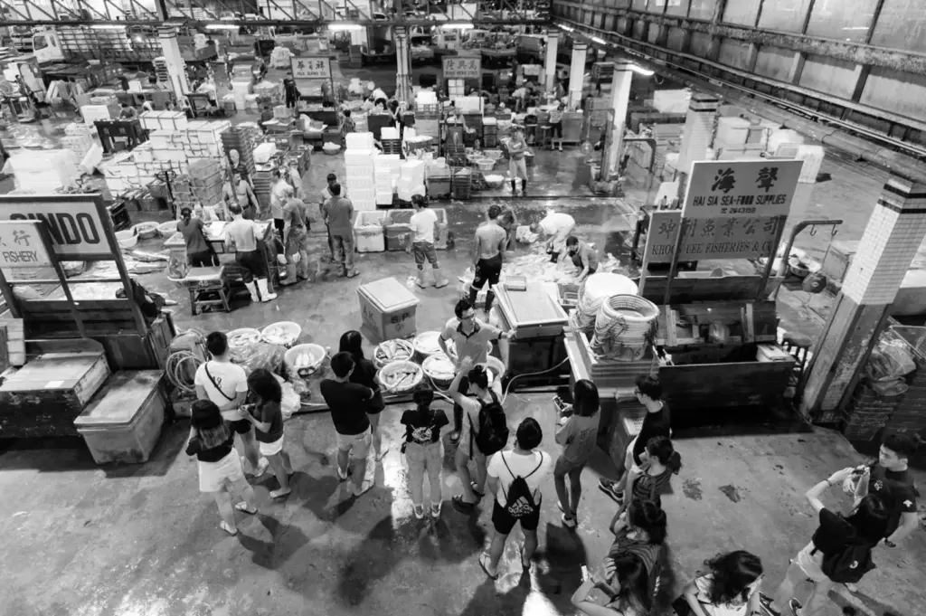 Busy Singapore fish market filled with seafood vendors, crates, and customers