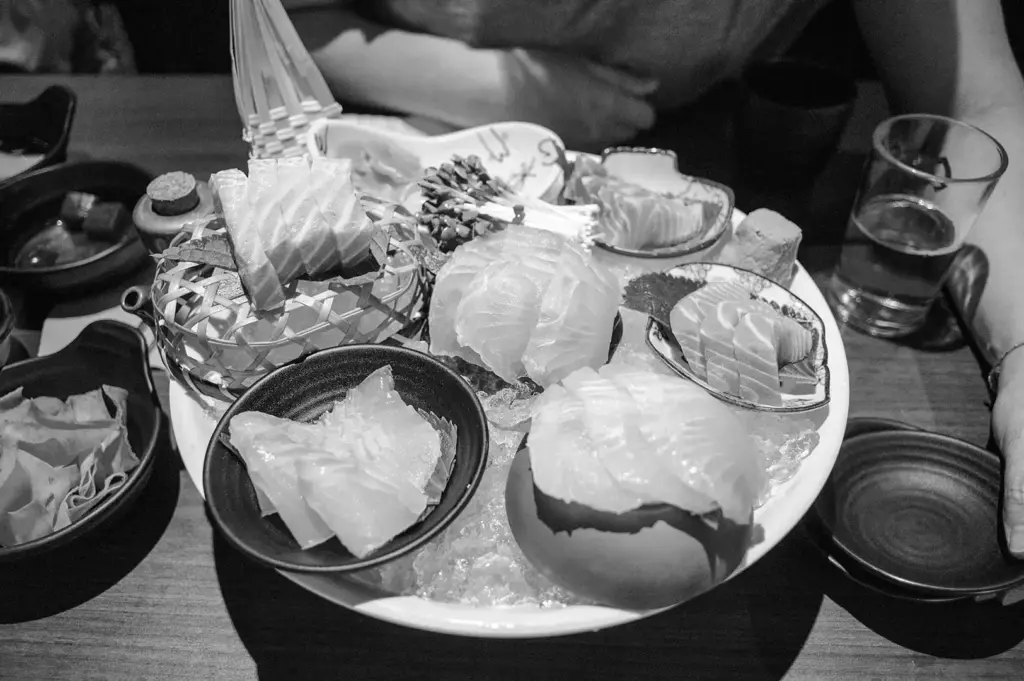 A platter of assorted sashimi served over crushed ice with dipping sauces and garnishes.
