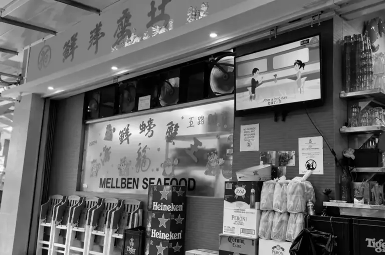 Mellben Seafood restaurant storefront with signage, stacked beer crates, and outdoor seating.