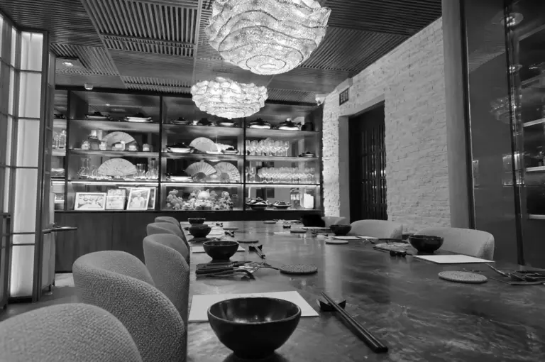 Elegant restaurant interior with a long dining table, decorative chandeliers, and refined table settings in a luxury dining space.