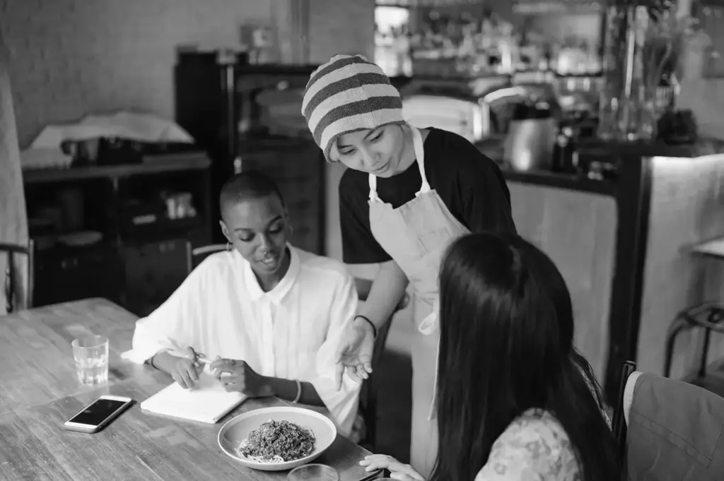 Restaurant staff member assisting diners at their table, showing the human side of hospitality.
