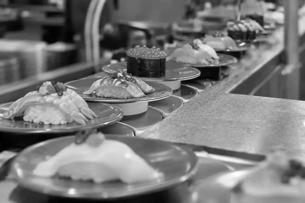Sushi plates moving along a conveyor belt at a kaitenzushi restaurant, showcasing the self-service dining experience.